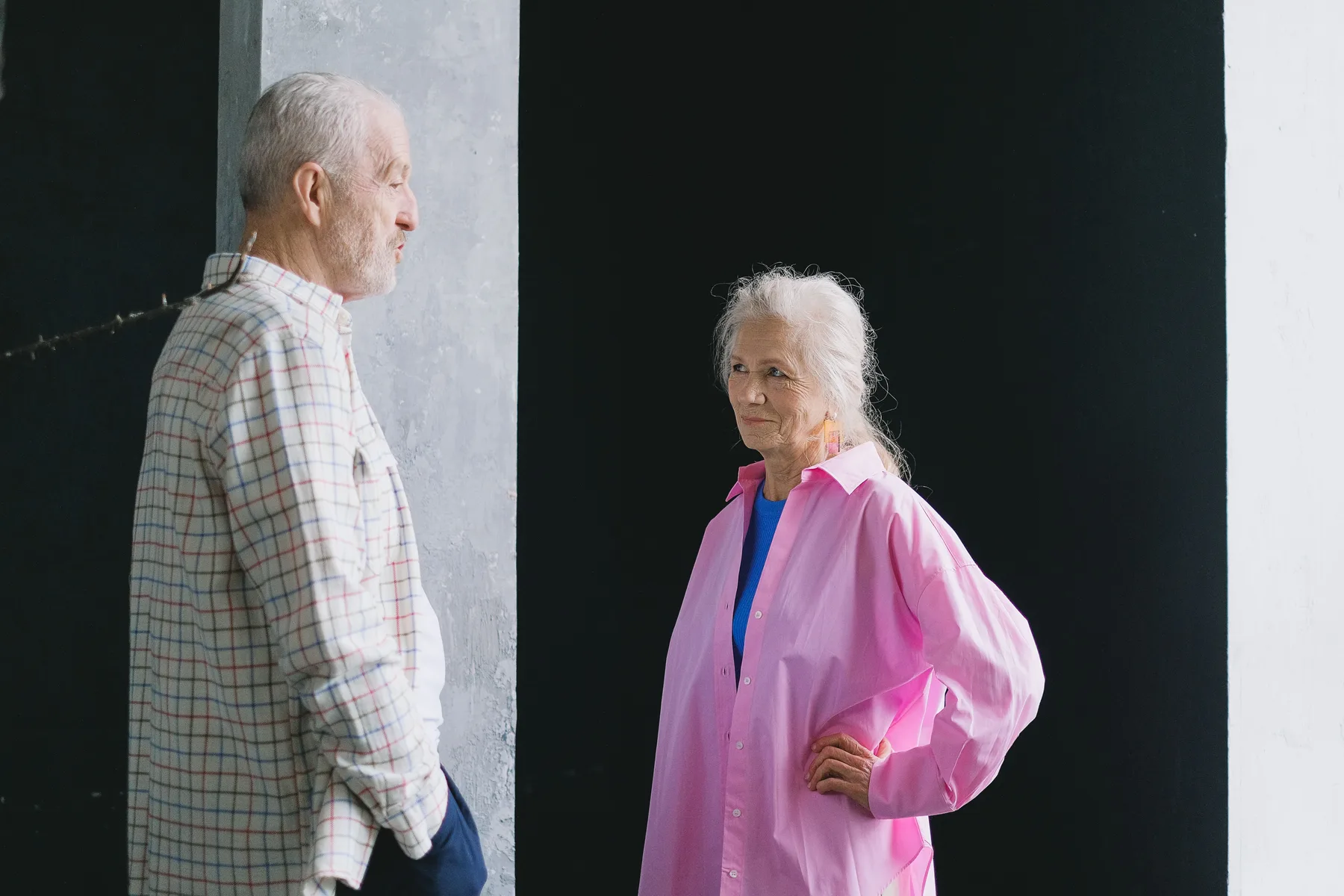 An older couple stand facing one another and talk while making eye contact